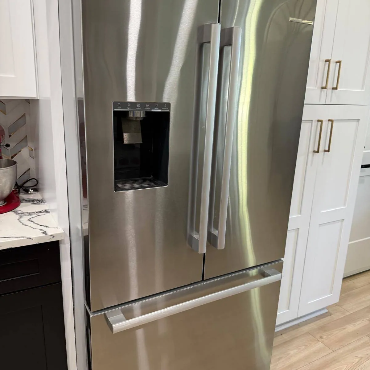 Kitchen after cleaning: stainless refrigerator and white cabinets